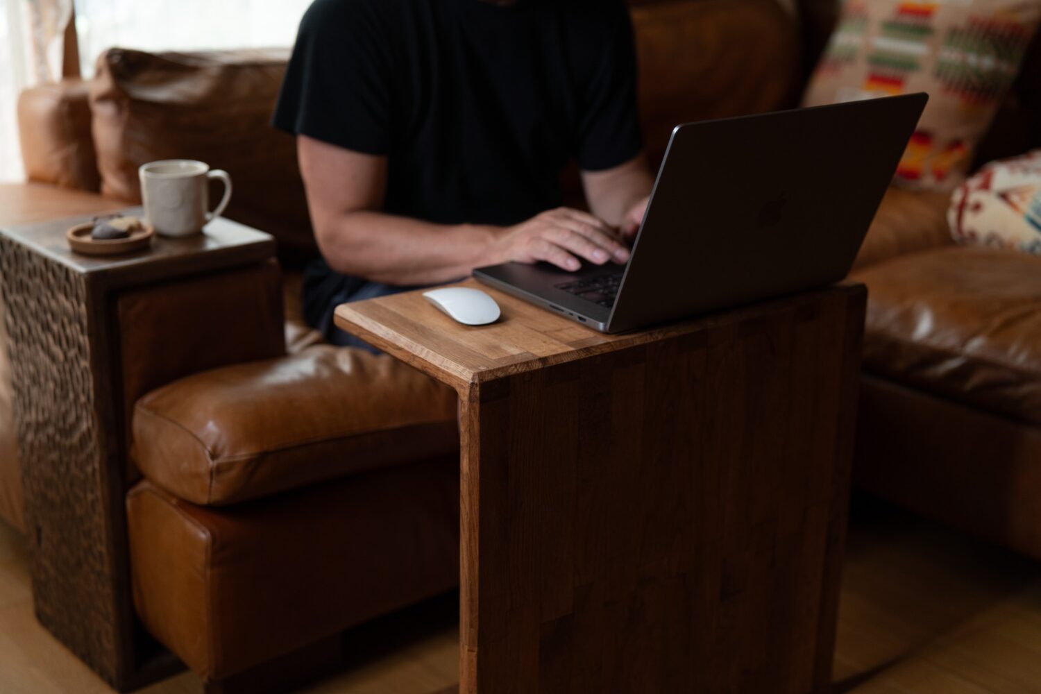 ソファーに座りコンパクトデスクでMacBookを使っている様子